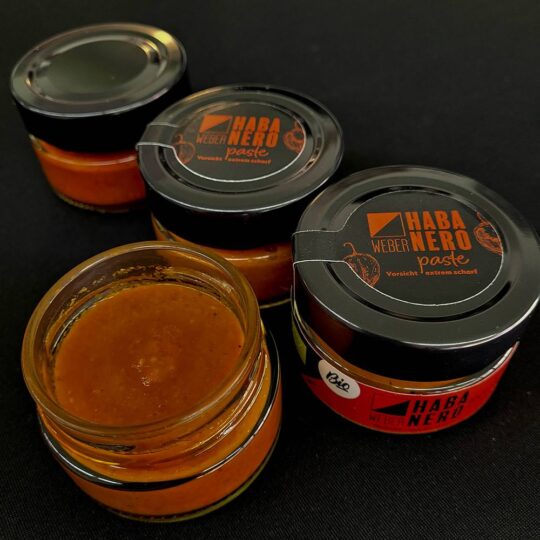 Die “Bio Habanero Chilipaste” ist die ultimative Wahl für alle, die die pure, ungebändigte Schärfe lieben. Mit einem beeindruckenden Anteil von 89% frischen Habanero-Chilis aus Oberösterreich und dem Burgenland bringt diese Paste intensive Hitze und authentischen Geschmack in jedes Gericht. Ohne Essig, Zucker oder Konservierungsstoffe hergestellt, verkörpert sie den reinen, unverfälschten Geschmack der Habanero-Chili. Ein Hauch von griechischem Olivenöl und eine Prise Steinsalz runden diese Chilipaste ab, ohne die Schärfe zu mildern. Sie eignet sich perfekt, um Gerichten einen kräftigen, feurigen Kick zu verleihen, sei es in Saucen, Marinaden oder als Würze für Fleisch und Gemüse. Besonders wichtig: Nach dem ersten Öffnen sollte die Paste immer mit einer Schicht Olivenöl bedeckt und im Kühlschrank gelagert werden, um die Frische und Intensität der Chilis zu bewahren. Diese Bio Habanero Chilipaste ist ein Muss für alle, die es ernst meinen mit Schärfe und die authentischen, biologische Produkte schätzen.