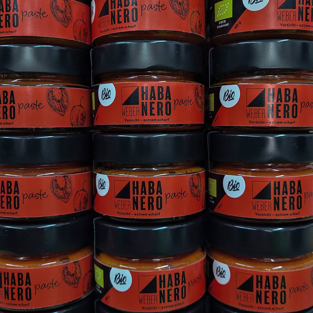 Die “Bio Habanero Chilipaste” ist die ultimative Wahl für alle, die die pure, ungebändigte Schärfe lieben. Mit einem beeindruckenden Anteil von 89% frischen Habanero-Chilis aus Oberösterreich und dem Burgenland bringt diese Paste intensive Hitze und authentischen Geschmack in jedes Gericht. Ohne Essig, Zucker oder Konservierungsstoffe hergestellt, verkörpert sie den reinen, unverfälschten Geschmack der Habanero-Chili. Ein Hauch von griechischem Olivenöl und eine Prise Steinsalz runden diese Chilipaste ab, ohne die Schärfe zu mildern. Sie eignet sich perfekt, um Gerichten einen kräftigen, feurigen Kick zu verleihen, sei es in Saucen, Marinaden oder als Würze für Fleisch und Gemüse. Besonders wichtig: Nach dem ersten Öffnen sollte die Paste immer mit einer Schicht Olivenöl bedeckt und im Kühlschrank gelagert werden, um die Frische und Intensität der Chilis zu bewahren. Diese Bio Habanero Chilipaste ist ein Muss für alle, die es ernst meinen mit Schärfe und die authentischen, biologische Produkte schätzen.