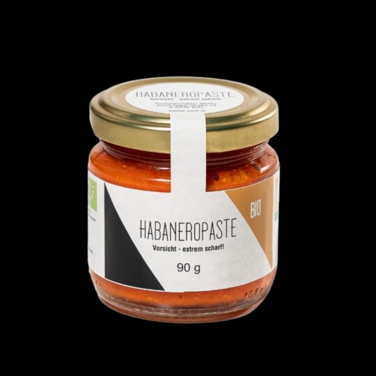 Die “Bio Habanero Chilipaste” ist die ultimative Wahl für alle, die die pure, ungebändigte Schärfe lieben. Mit einem beeindruckenden Anteil von 89% frischen Habanero-Chilis aus Oberösterreich und dem Burgenland bringt diese Paste intensive Hitze und authentischen Geschmack in jedes Gericht. Ohne Essig, Zucker oder Konservierungsstoffe hergestellt, verkörpert sie den reinen, unverfälschten Geschmack der Habanero-Chili. Ein Hauch von griechischem Olivenöl und eine Prise Steinsalz runden diese Chilipaste ab, ohne die Schärfe zu mildern. Sie eignet sich perfekt, um Gerichten einen kräftigen, feurigen Kick zu verleihen, sei es in Saucen, Marinaden oder als Würze für Fleisch und Gemüse. Besonders wichtig: Nach dem ersten Öffnen sollte die Paste immer mit einer Schicht Olivenöl bedeckt und im Kühlschrank gelagert werden, um die Frische und Intensität der Chilis zu bewahren. Diese Bio Habanero Chilipaste ist ein Muss für alle, die es ernst meinen mit Schärfe und die authentischen, biologische Produkte schätzen.